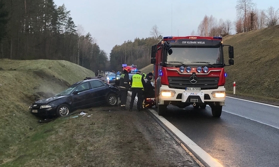 auto w rowie, funkcjonariusze Policji i Straży Pożarnej stojący przy wozie strażackim.