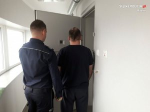 policjant prowadzi zatrzymanego podpalacza