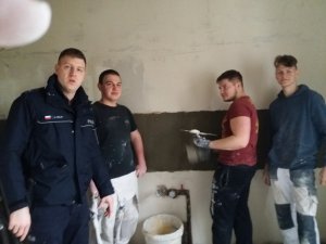 Policjant w towarzystwie mężczyzn remontujących lokal (podczas pracy)