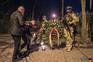 Policjanci zapalają znicze pod pomnikiem