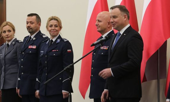 Prezydent Andrzej Duda podczas przemówienia w tle Komendant Główny Policji i Rektor WSPol