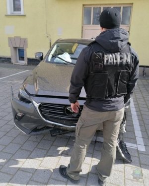 policjant stoi przy zabezpieczonym samochodzie