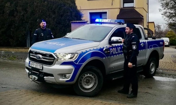 dwaj policjanci stoją przy radiowozie