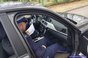 policjant ruchu drogowego siedzi w nieoznakowanym radiowozie z wideorejestratorem