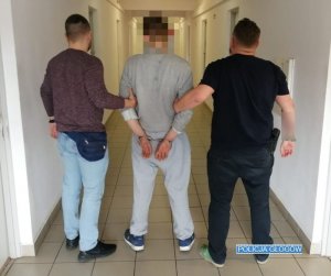 Policjanci prowadzą trzeciego zatrzymanego mężczyznę