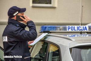 policjant rozmawia przez telefon z osobą poddaną kwarantannie