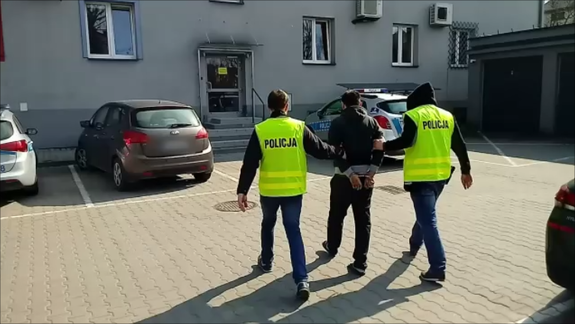 policjanci kryminalni prowadzą zatrzymanego do jednostki Policji