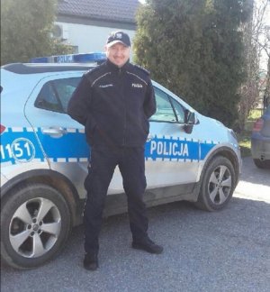 Umundurowany policjant przed radiowozem