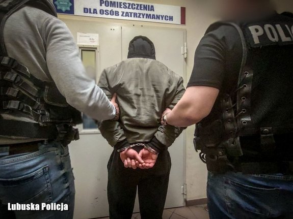 zatrzymany mężczyzna prowadzony przez dwóch policjantów