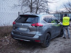 policjant stoi przy samochodzie nissan x-trail