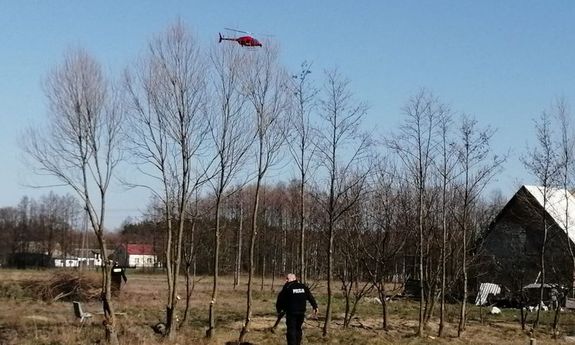 Policjant szuka zaginionej na polu nad nim policyjny helikopter