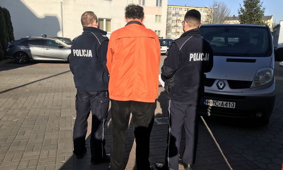 Zatrzymany mężczyzna w eskorcie dwóch policjantów