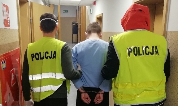 dwaj policjanci prowadzą zatrzymanego mężczyznę