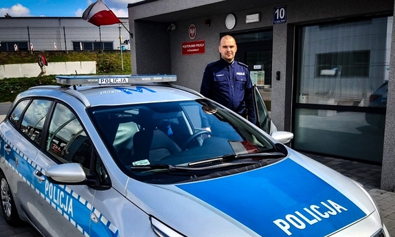 policjant stoi obok radiowozu policyjnego