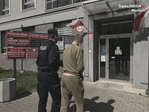 Policjant prowadzi zatrzymanego