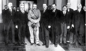 Na zdjęciu mężczyzna w mundurze otoczony innymi mężczyznami ubranymi w garnitury