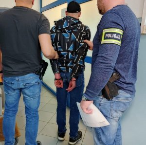 dwaj policjanci prowadzą zatrzymanego mężczyznę
