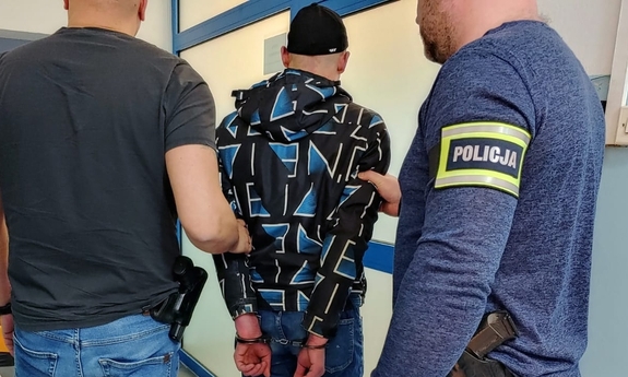 dwaj policjanci prowadzą zatrzymanego mężczyznę