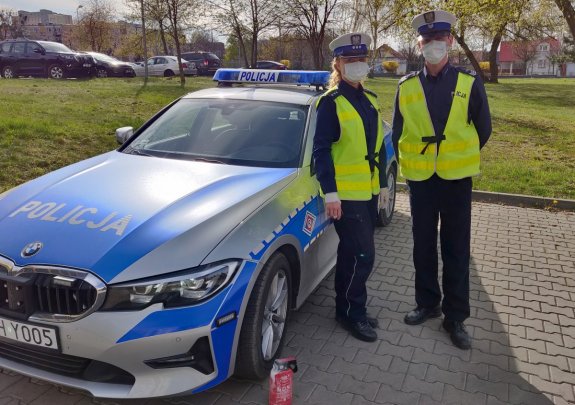 Policjant i Policjantka na tle oznakowanego radiowozu