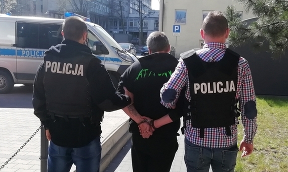 dwaj policjanci prowadzą zatrzymanego mężczyznę