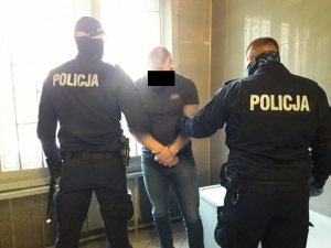 Zatrzymany pilnowany przez dwóch policjantów