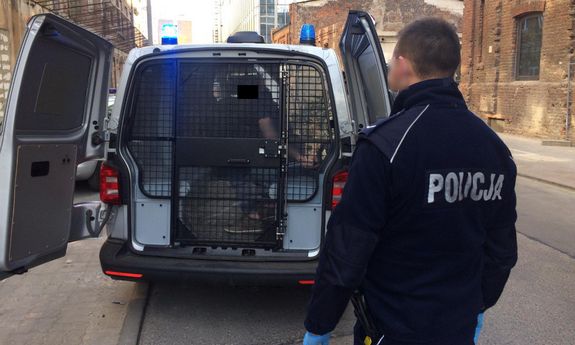 Policjant w tle radiowóz z zatrzymanym