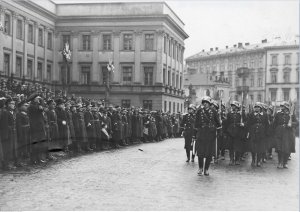 czarno-białe zdjęcie przedstawia żołnierzy maszerujących przez miasto podczas defilady