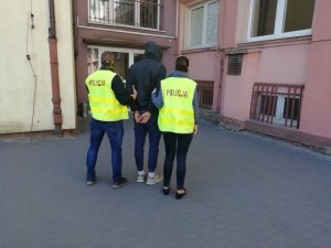 dwaj policjanci prowadzą zatrzymanego mężczyznę