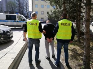 dwaj policjanci prowadzą zatrzymanego mężczyznę