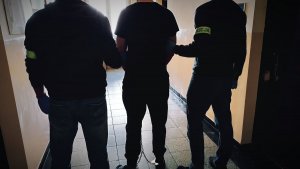 dwaj policjanci prowadzą zatrzymanego mężczyznę