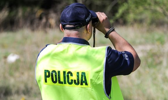 policjant podczas poszukiwań patrzy przez lornetkę