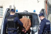 zatrzymany przez policjantów wchodzi do radiowozu policyjnego