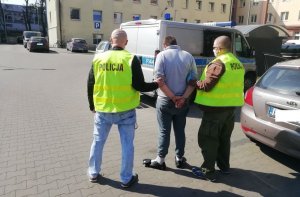 dwaj policjanci prowadzą zatrzymanego mężczyznę