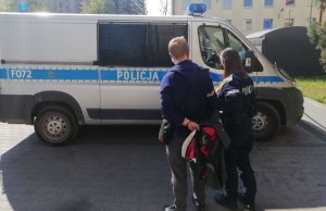 policjantka prowadzi do radiowozu zatrzymanego mężczyznę