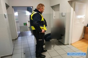 policjant pilnuje zatrzymanego, który siedzi na krześle