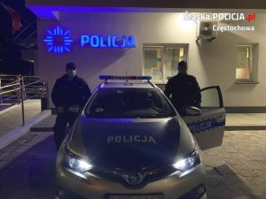 dwaj policjanci stoją przy radiowozie