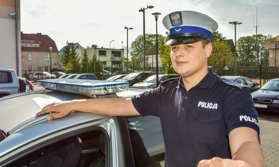 policjant stoi przy radiowozie