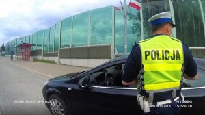 umundurowany policjant przy radiowozie - zrzut ekranu zrobiony z filmu z kamery nasobnej umieszczonej na mundurach