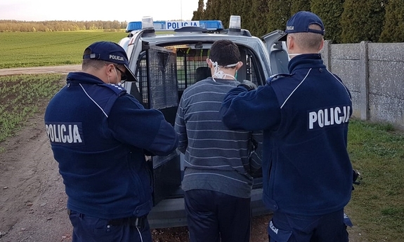 Policjanci prowadzą zatrzymanego do radiowozu