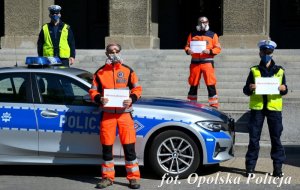 policjanci i ratownicy medyczni stoją obok siebie w ręce trzymając kartkę z napisem #murem za medykiem&quot;&gt;