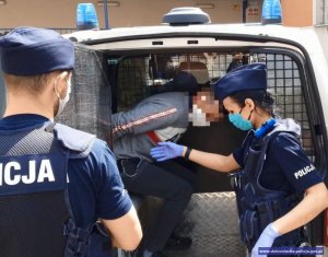 policjanci umieszczają zatrzymanego w radiowozie