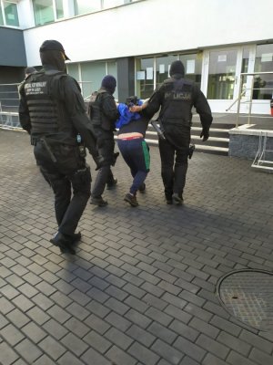 policjanci prowadzą zatrzymanego mężczyznę