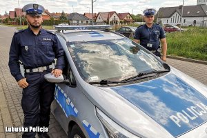 dwaj policjanci w mundurach przy radiowozie