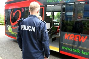 Zdjęcie kolorowe. Policjant obok autobusu RCKiK&quot;&gt;