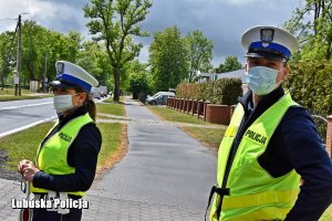 policjant i policjantka stojący przy drodze