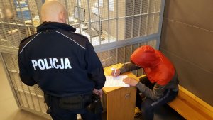 policjant z zatrzymanym mężczyzną w areszcie