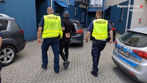 dwaj policjanci prowadzą zatrzymanego mężczyznę