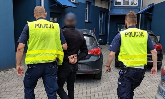 dwaj policjanci prowadzą zatrzymanego mężczyznę