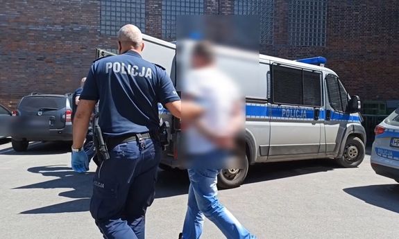 Policjant prowadzi zatrzymanego mężczyznę