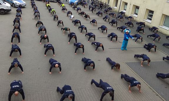 policjanci robią pompki na placu